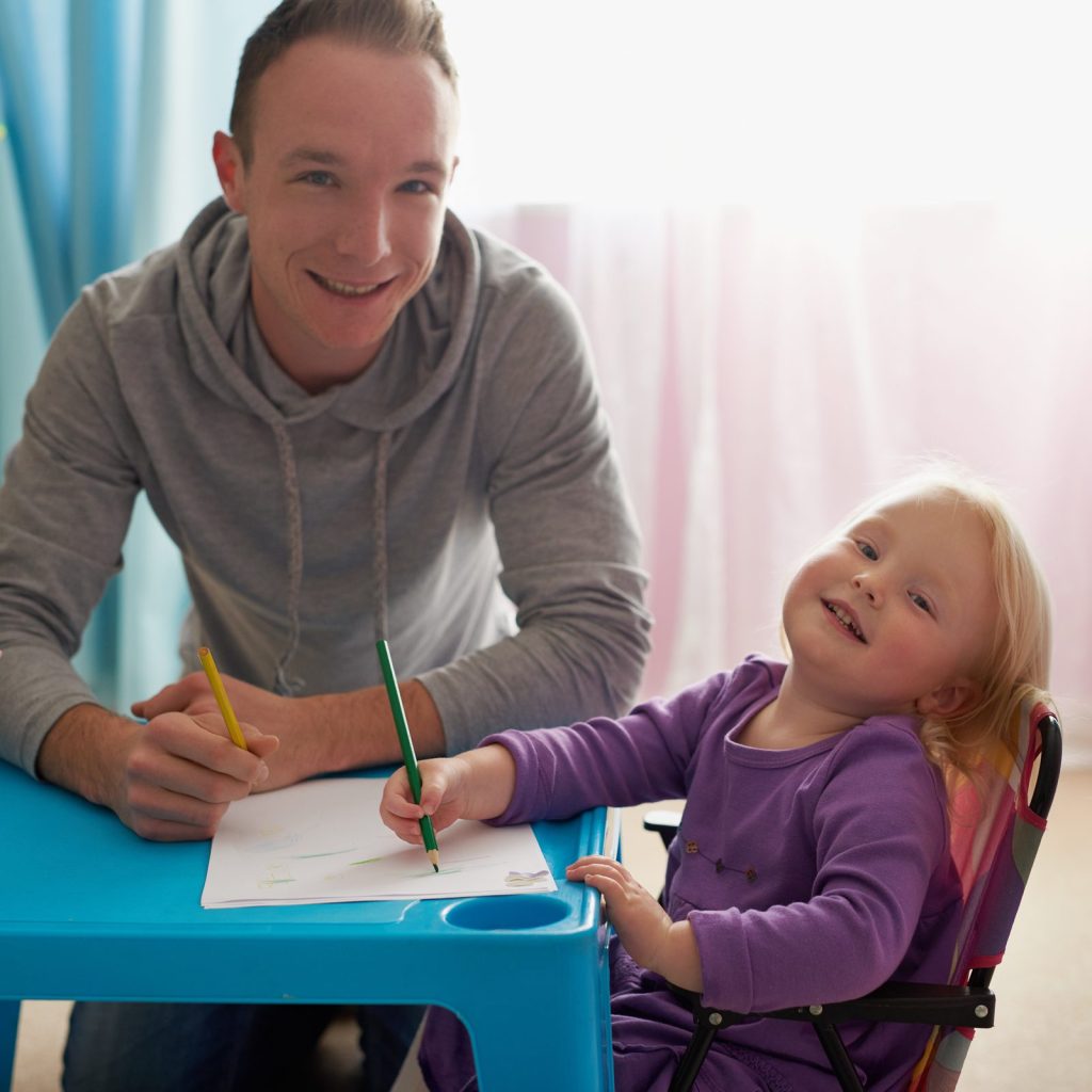 A toddler drawing with a teacher at a small table
