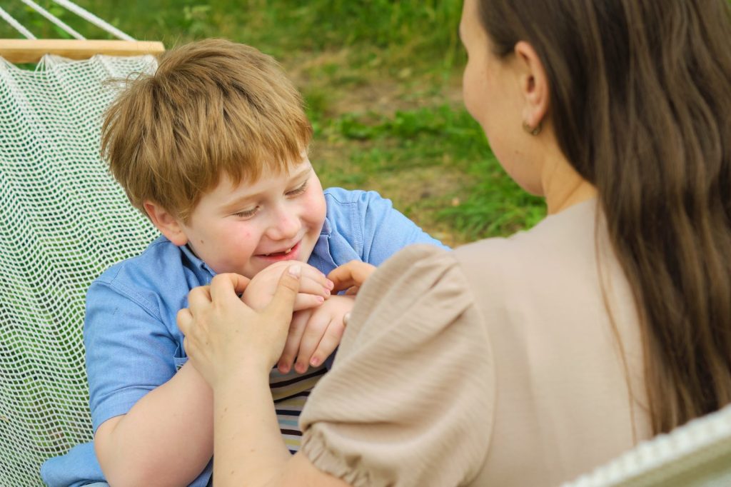A smiling boy with his mother in a hammock