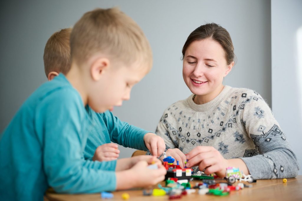 A mother and two boys building a toy model